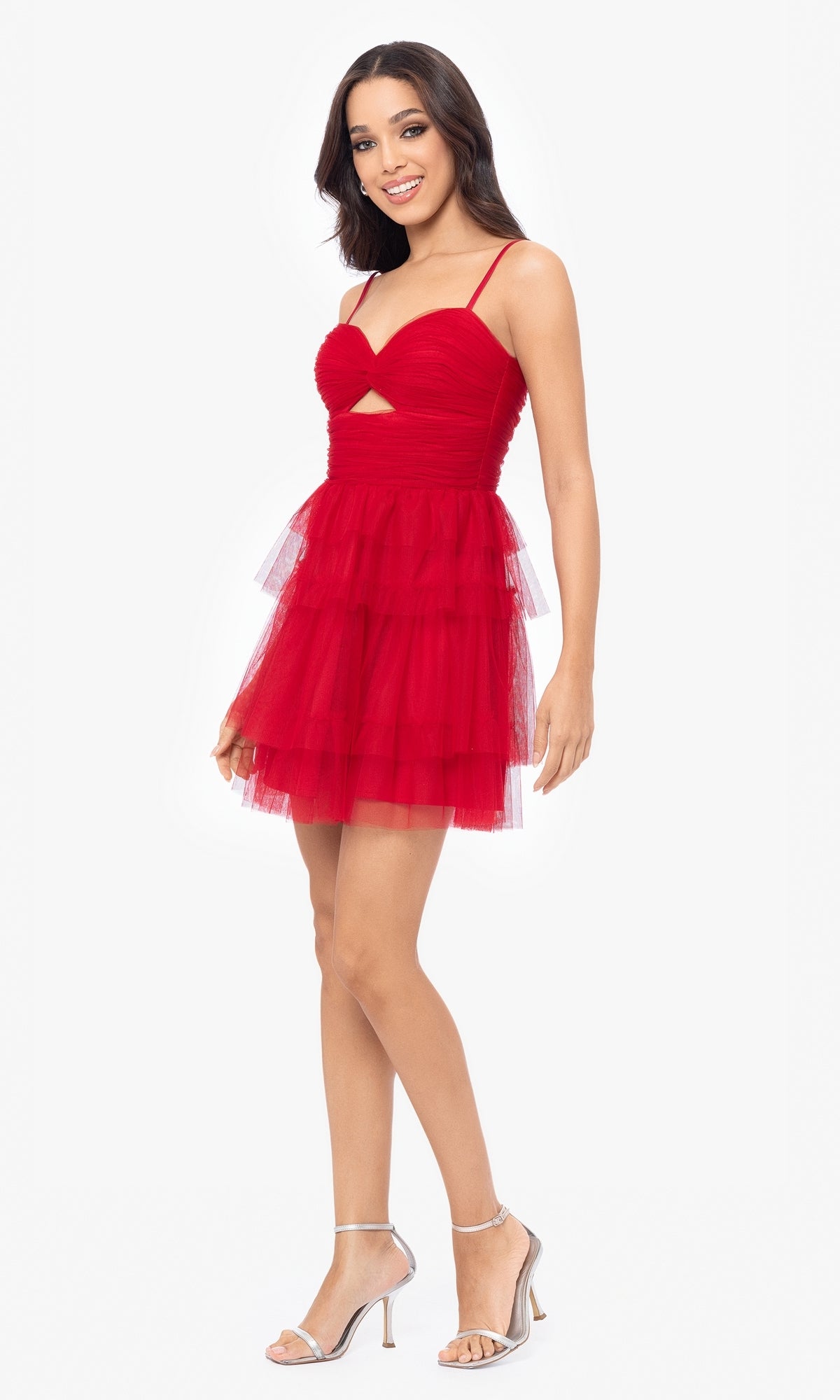 Woman modeling the Cut-Out Short Ruffled Homecoming Dress 5098BN—sleeveless, tiered skirt, ruched sweetheart bodice—stands smiling in strappy heels against a plain white background.